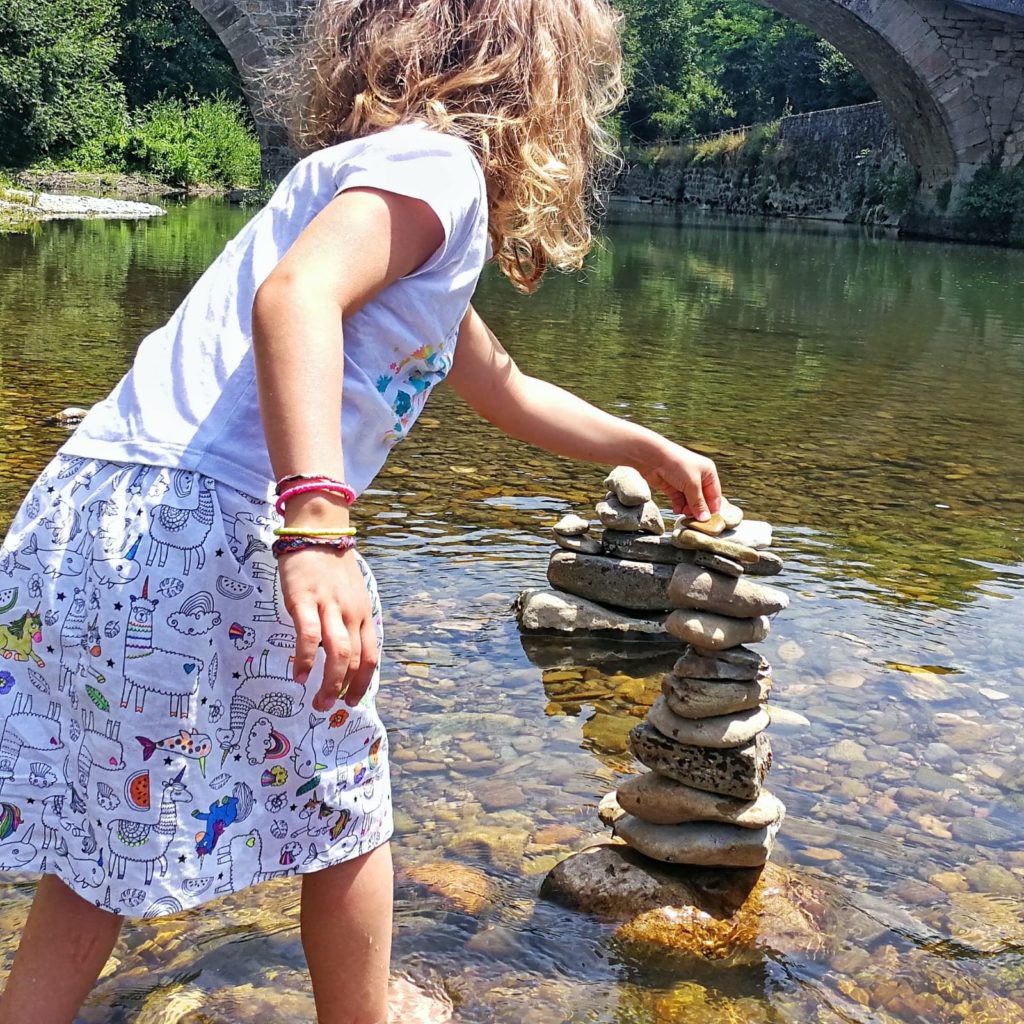 Petite fille jouant dans une riviere avec une jupe couture